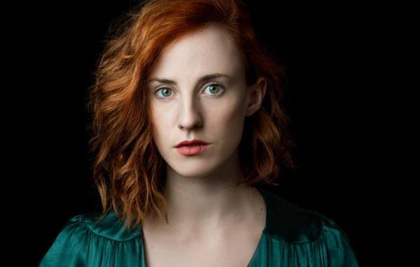 Красивая зеленоглазая рыжеволосая девушка на черном фоне 