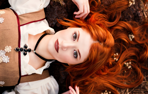 Красивая рыжеволосая девушка лежит на земле 