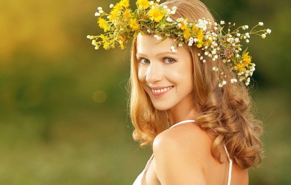 Красивая улыбающаяся девушка с венком из полевых цветов на голове