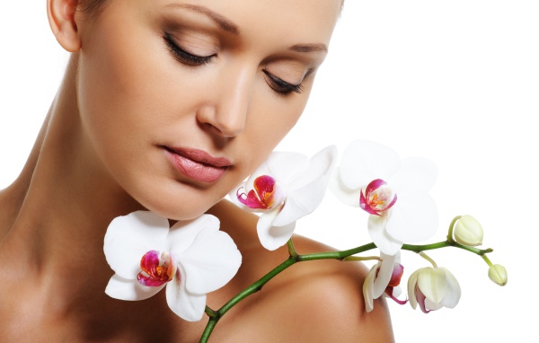 Красивая нежная девушка с цветами орхидеи на белом фоне