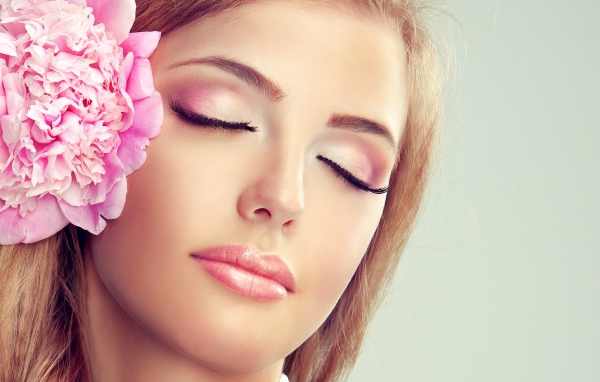 Красивая нежная молодая девушка с розовым цветком пиона в волосах 