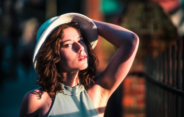 Красивая молодая девушка в белой шляпе в свете солнца