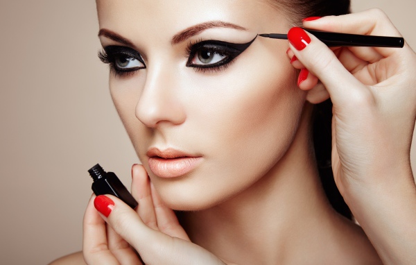 Красивой молодой девушке модели делают макияж глаз