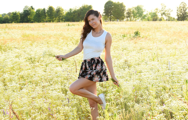 Красивая молодая девушка на поле с белыми ромашками