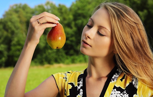 Красивая молодая девушка с грушей в руках