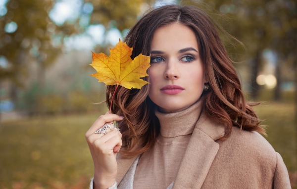 Красивая молодая девушка шатенка с желтым листом в руке