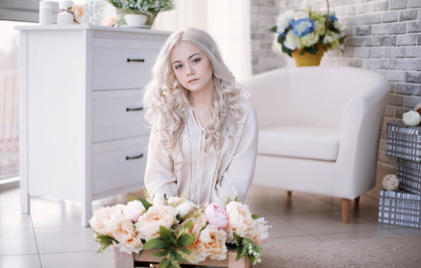 Девушка блондинка с пионами сидит в комнате