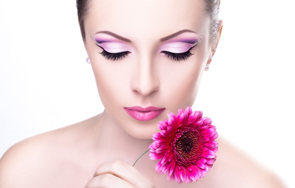 Нежная девушка с розовым цветком герберы на белом фоне