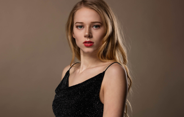 Нежная девушка модель в черном платье на сером фоне