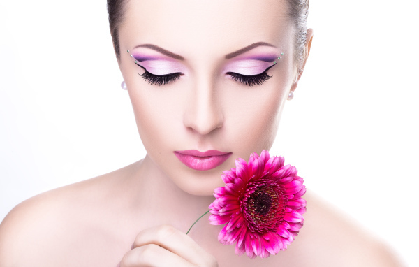 Девушка модель с нежным макияжем с розовым цветком герберы в руке