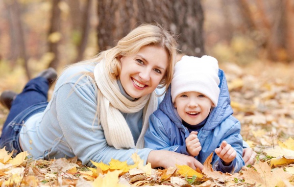 Мать с сыном лежат на листве осенью