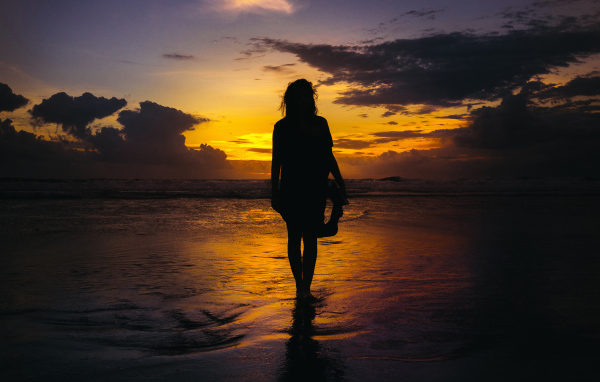 Силуэт красивой девушки на берегу моря на закате