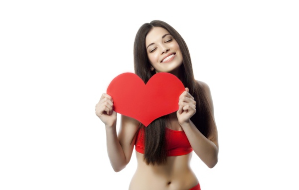 Улыбающаяся брюнетка с красным сердцем в руках на белом фоне
