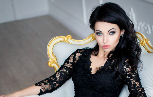Эффектная брюнетка в черном платье сидит в кресле