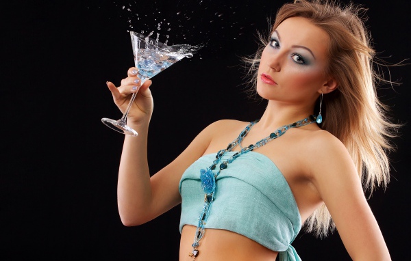 Эффектная молодая девушка с коктейлем в руках на черном фоне