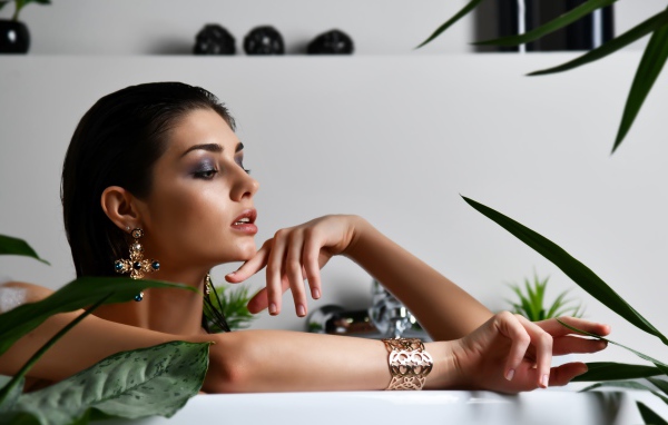 Девушка в дорогих украшения лежит в ванной