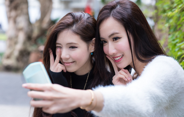 Две девушки азиатки делают селфи