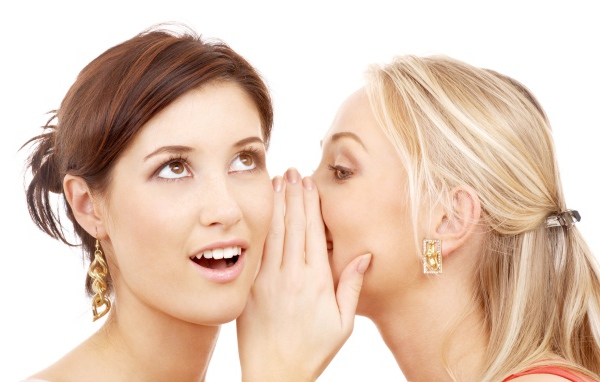 Две подруги делятся секретами на белом фоне 