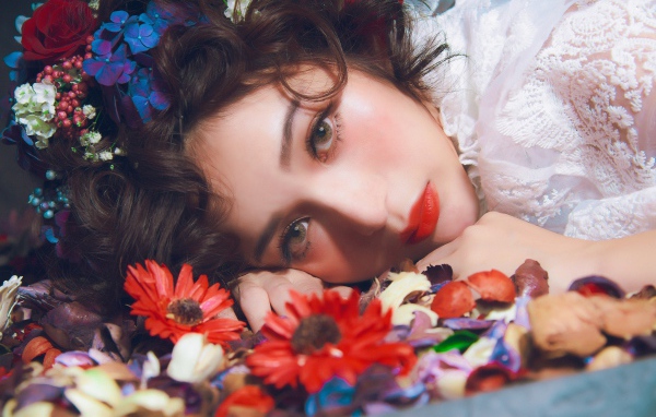 Молодая красивая девушка лежит цветами в волосах