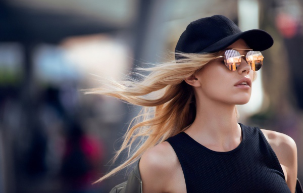 Молодая блондинка в солнечных очках и черной кепке 