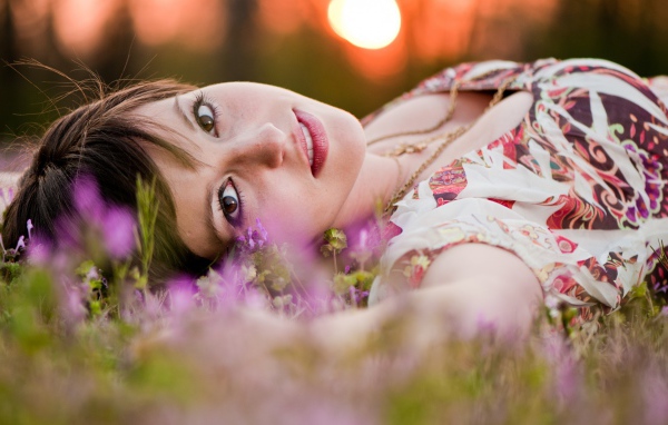 Молодая кареглазая девушка лежит на траве