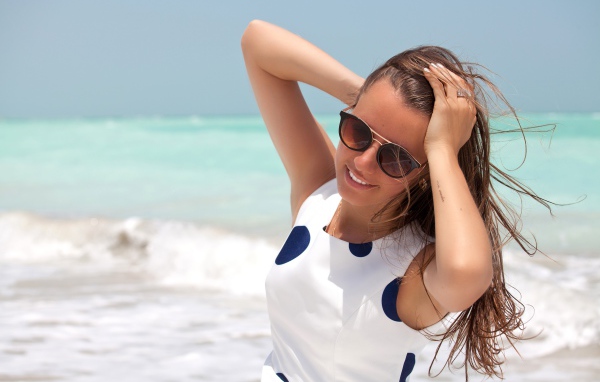 Молодая шатенка в солнечных очках у моря