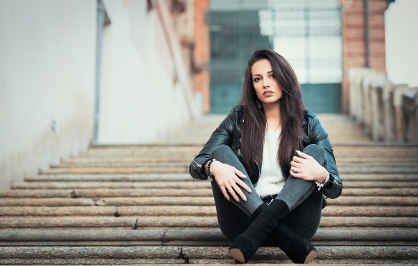 Молодая брюнетка сидит на ступеньках