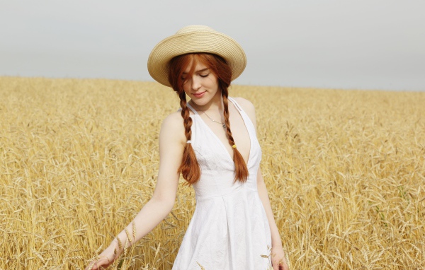 Молодая девушка в белом платье на поле с пшеницей