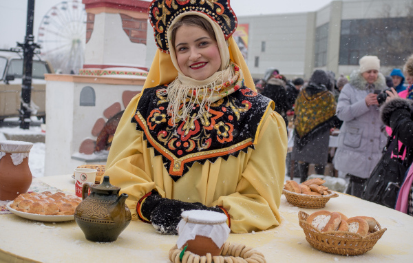 Красивая молодая девушка с угощениями на Масленицу 2018