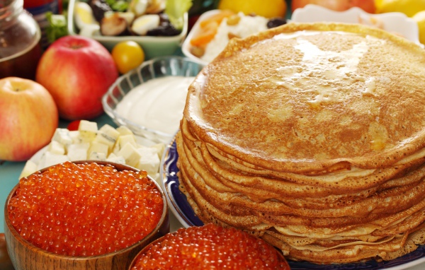 Румяные тонкие блины на столе с красной икрой на Масленицу