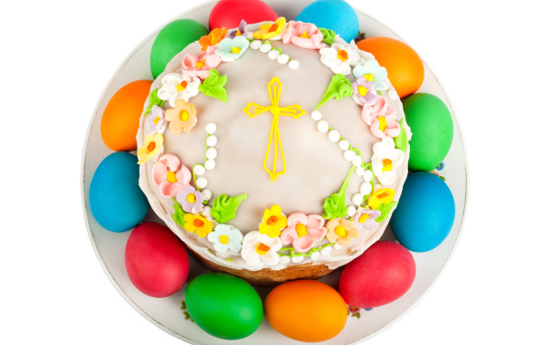 Красивый пасхальный кулич с цветами и разноцветными крашеными яйцами на белом фоне