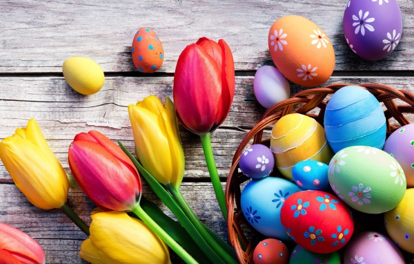 Крашеные яйца на столе с тюльпанами на Пасху