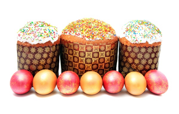 Три пасхальных кулича с крашеными яйцами на белом фоне на праздник Пасха