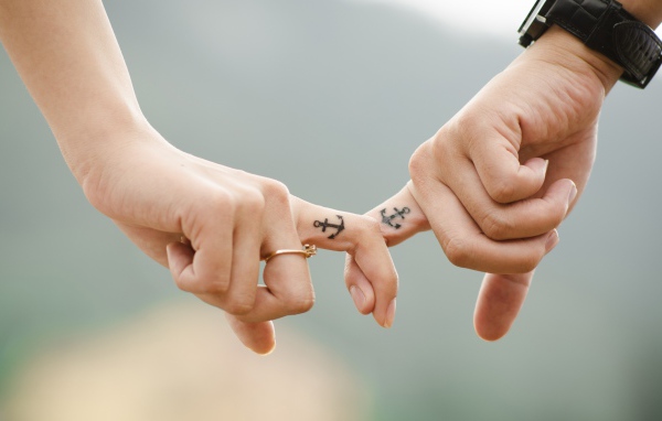 Hands of a loving couple with tattoos on their hands.