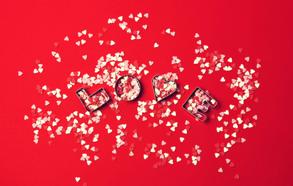 Надпись любовь из маленьких  сердечек на красном фоне