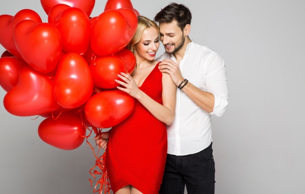 Влюбленная пара с красными воздушными шарами в форме сердца