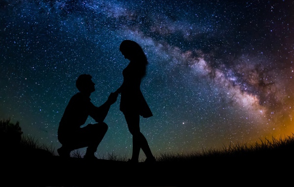 Силуэты влюбленной пары на фоне звездного неба ночью 