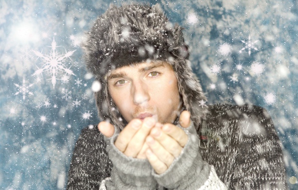 Молодой парень в теплой шапке мерзнет зимой