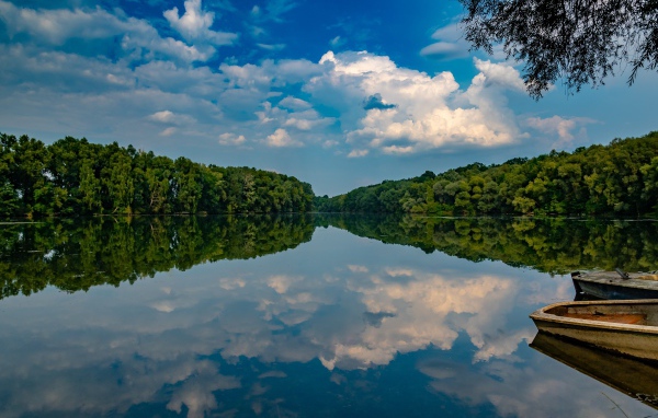 Beautiful blue sky and green forest reflected in the mirror of the lake