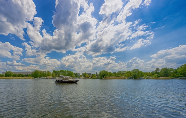 Катер на озере под красивым голубым небом с белыми облаками