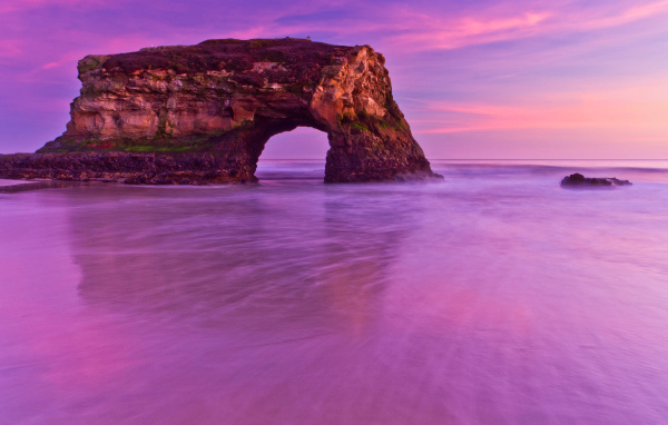 Гора с аркой в океане на фоне красивого неба