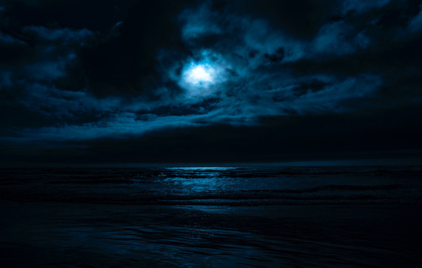 The moon in the cloudy sky over the sea at night