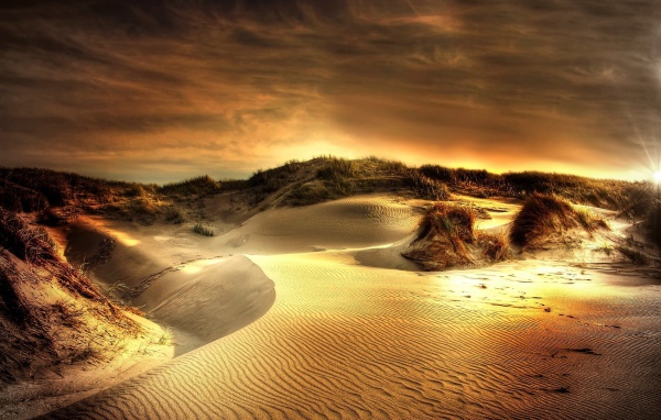 Волнистый песок под красивым небом на закате