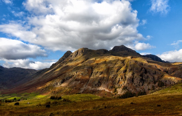 Белые пушистые облака над горой 