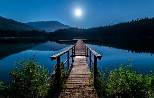 Деревянный мост на озере в полнолуние