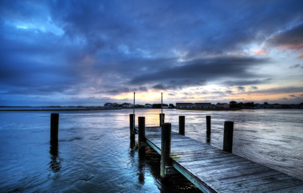 Деревянный мост на реке на фоне неба в сумерках