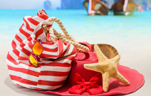 Большая красная шляпа с сумкой и морской звездой на пляже