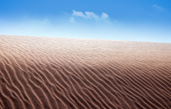 Песок в пустыне на фоне голубого неба