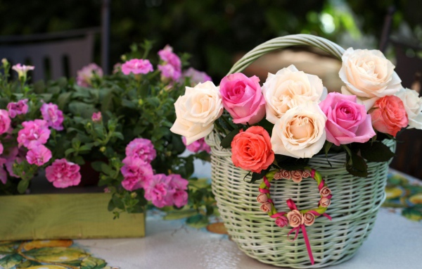 Букет нежных роз в корзине на столе с цветами