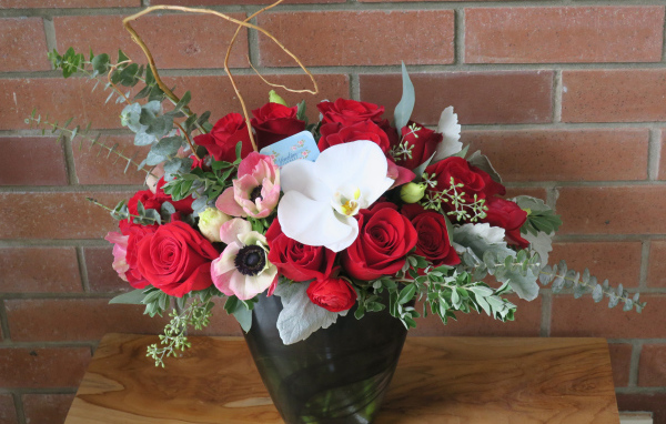 Букет с цветами анемоны, розы и орхидеи у стены 